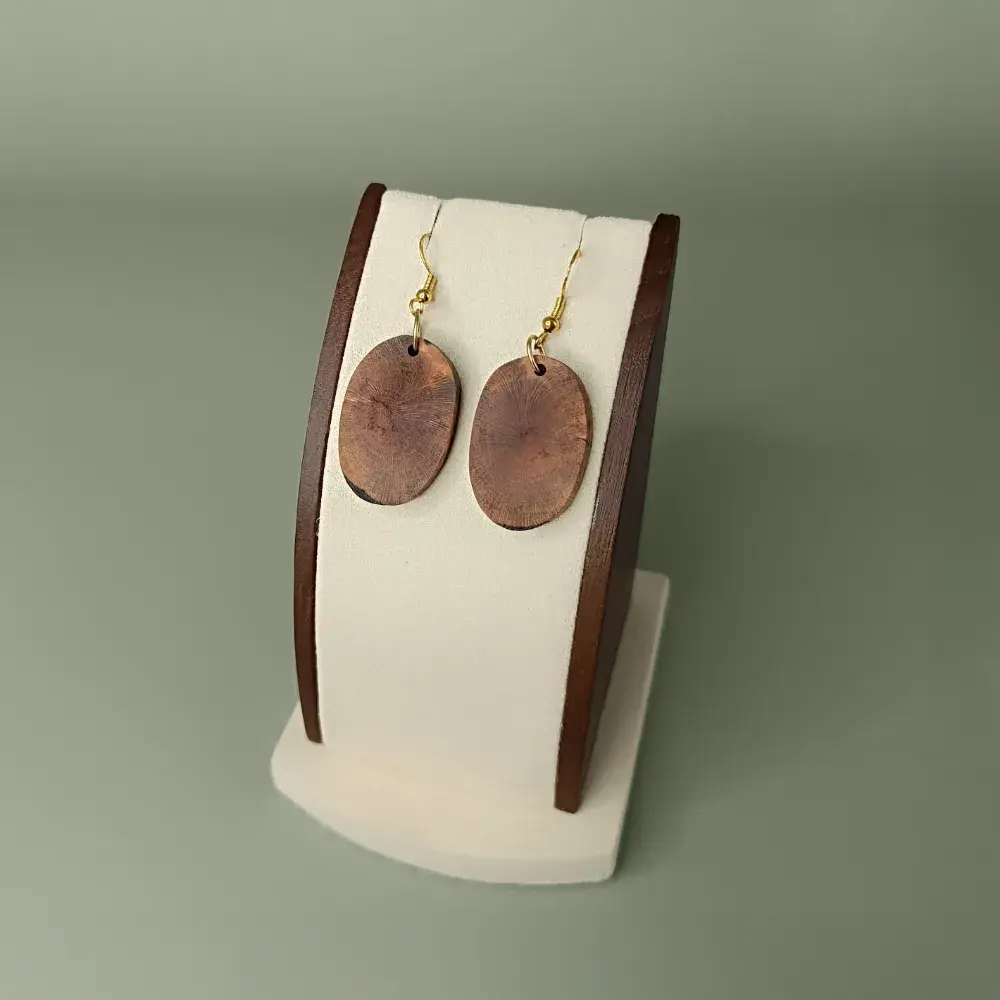 Bijoux artisanaux en bois flotté vue latérale sur support.