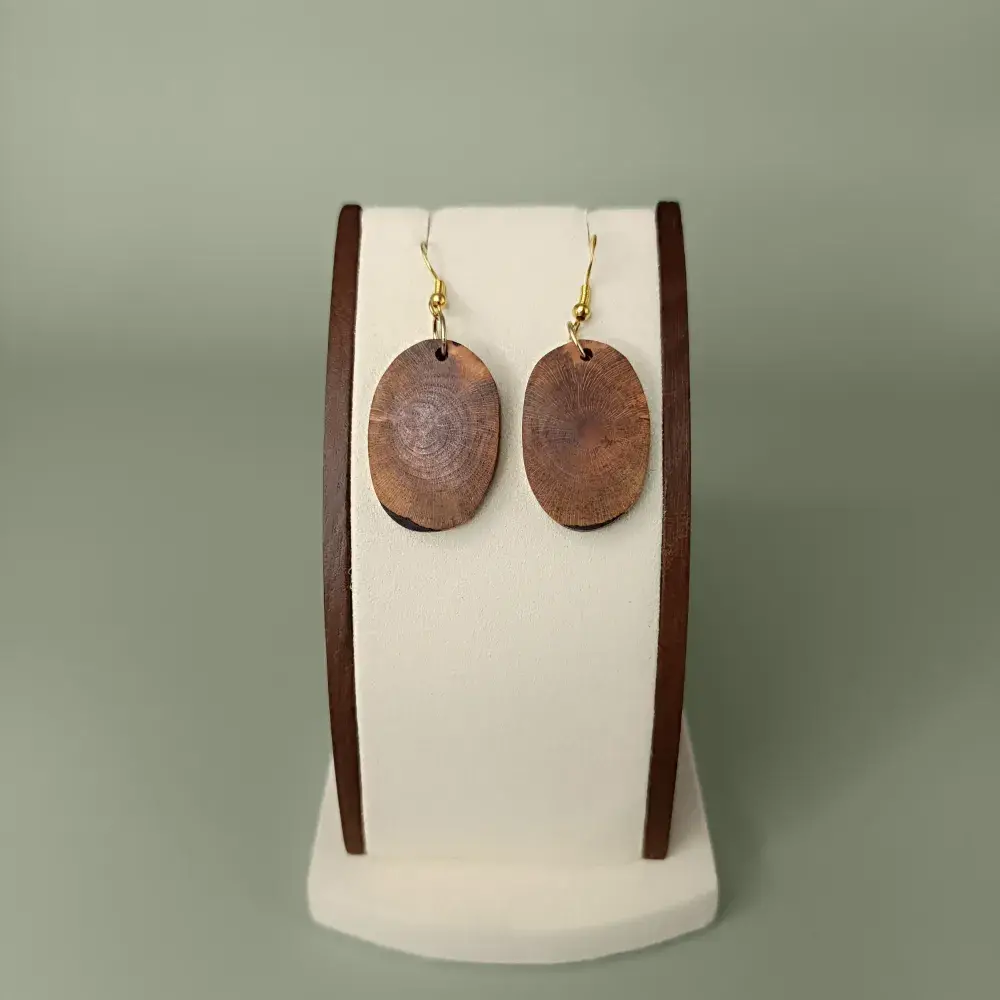 Boucles d’oreilles ovales en bois flotté naturel vue de face sur présentoir.