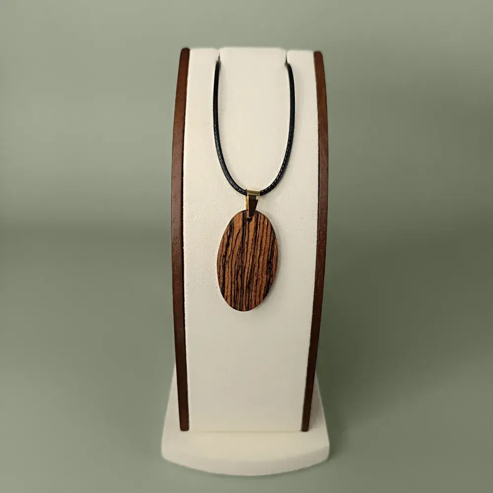 Vue de face du pendentif Écorce d’Or en bois de Bocote, forme ovale, veinages noirs et dorés subtils.