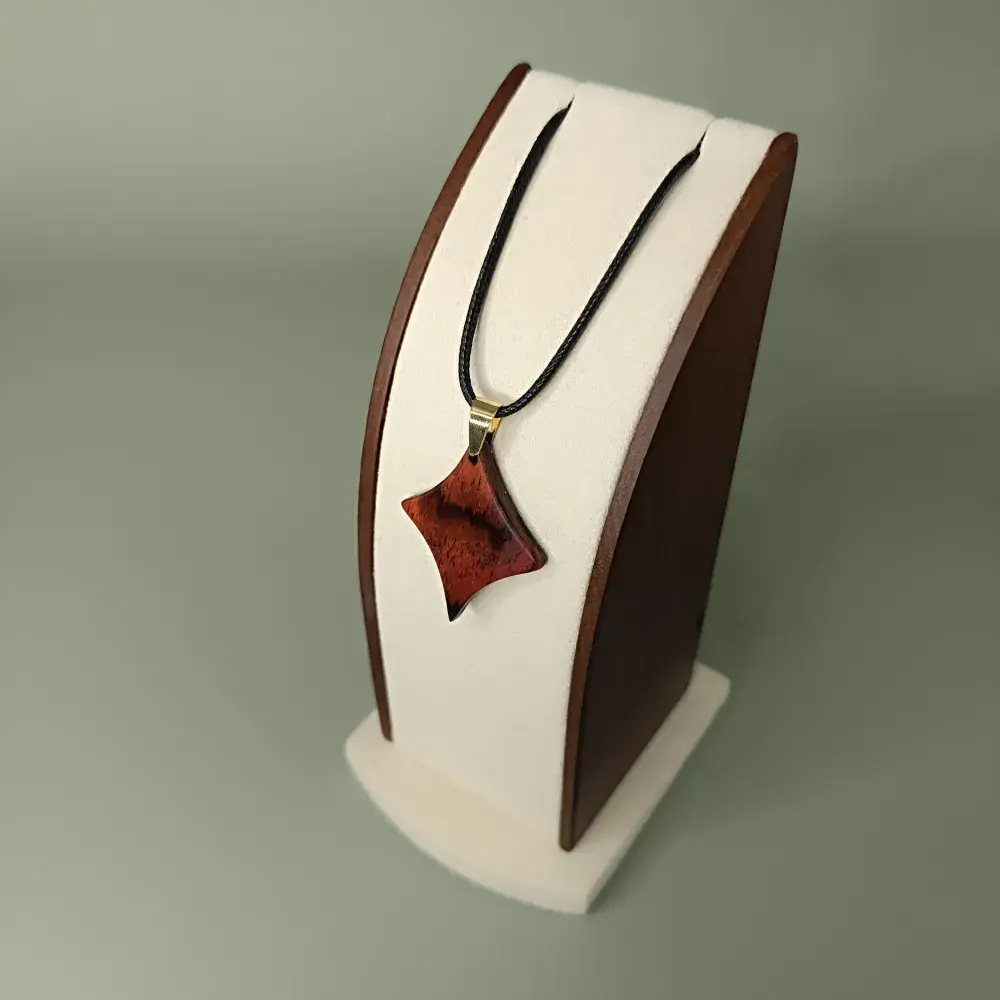 Plan latéral et plongeant du pendentif Braise Étoilée en bois de Cocobolo, forme étoile à quatre branches, veinages rouges et orangés.