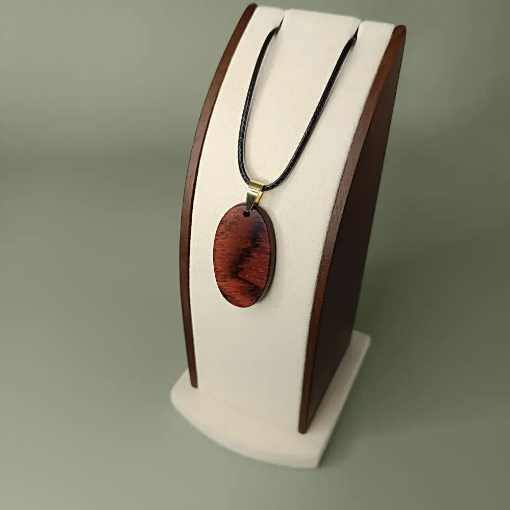 Plan latéral et plongeant du pendentif Éclat Naturel en bois de Cocobolo, forme ovale, veinages orangés et bruns subtils.