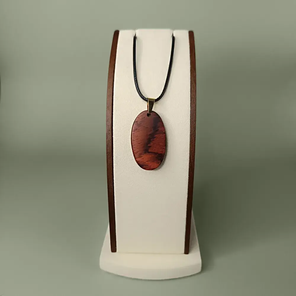 Vue de face du pendentif Éclat Naturel en bois de Cocobolo, forme ovale, veinages orangés et bruns subtils.