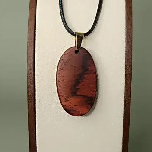 Pendentif Éclat Naturel en bois de Cocobolo, forme ovale, veinages orangés et bruns subtils.