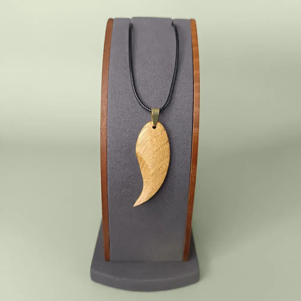 Pendentif artisanal en bois naturel avec cordon noir, création Skyline Artwood sur présentoir.
