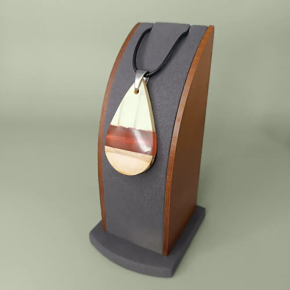 Pendentif en bois de pin et résine époxy rouge-orangé sur présentoir vue latérale.