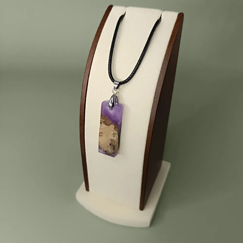 Pendentif artisanal en bois flotté et résine violette, vue latérale sur présentoir.