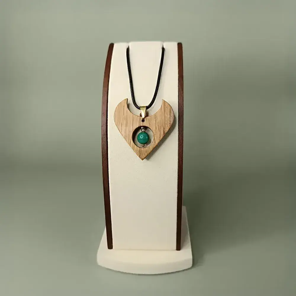 Pendentif en bois avec malachite claire, présenté de face sur un présentoir, style poétique et accessible.