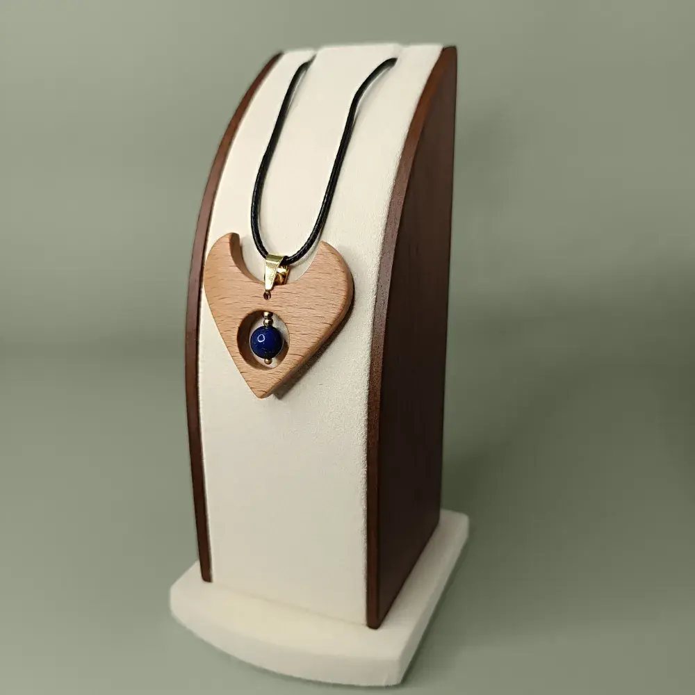 Pendentif en bois naturel avec lapis lazuli, forme fluide, présenté légèrement de côté sur un présentoir, semi-luxueux et poétique.