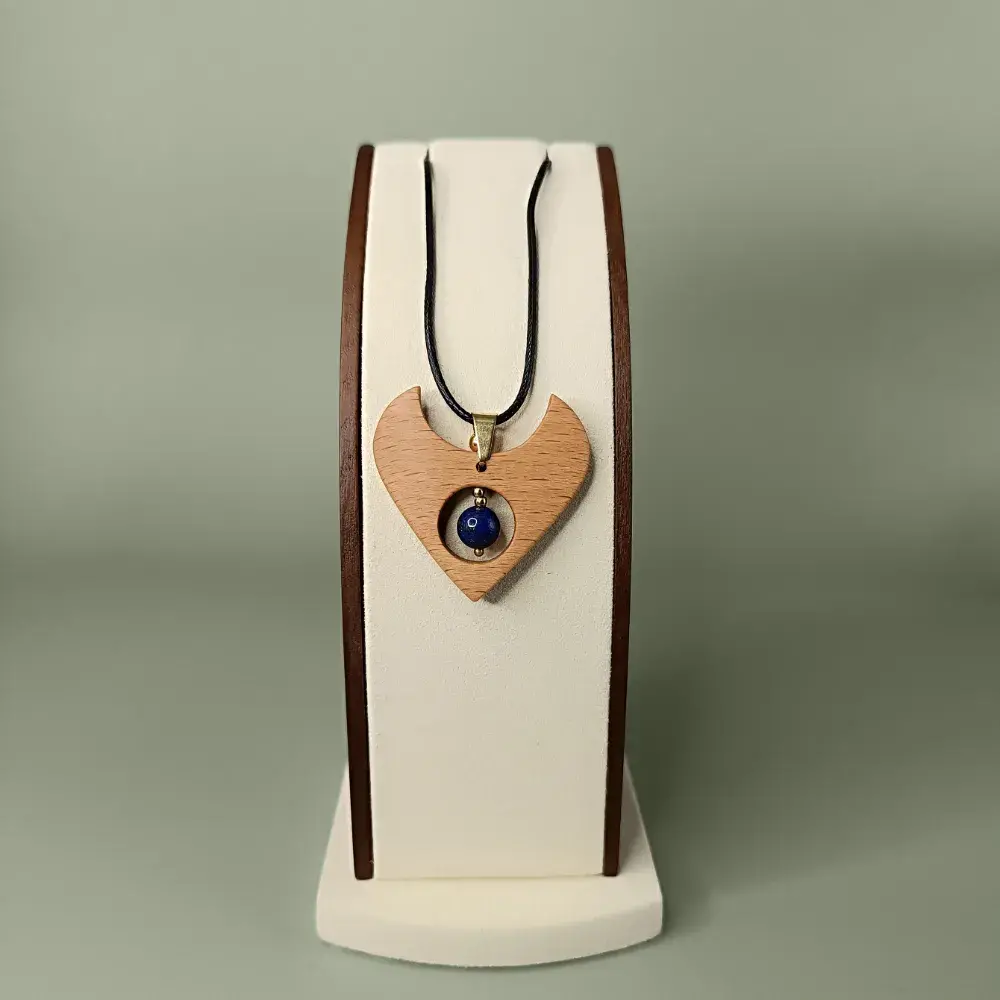 Pendentif en bois naturel avec lapis lazuli, forme fluide, présenté de face sur un présentoir, semi-luxueux et poétique.