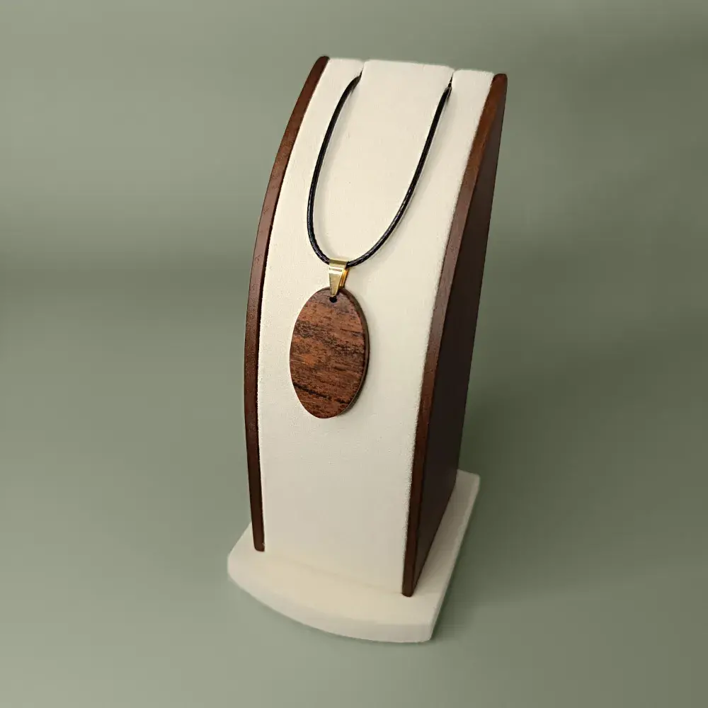 Plan latéral et plongeant du pendentif Soleil de Coton en bois Mahot Coton, forme ovale, veinages bruns chauds et dorés.