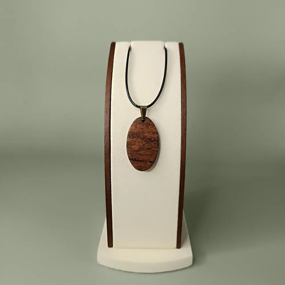 Vue de face du pendentif Soleil de Coton en bois Mahot Coton, forme ovale, veinages bruns chauds et dorés.