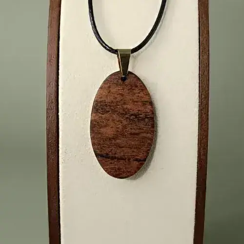 Pendentif Soleil de Coton en bois Mahot Coton, forme ovale, veinages bruns chauds et dorés.