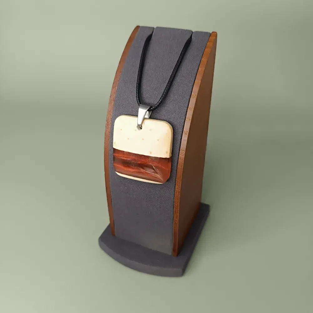 Pendentif carré en bois de pin et résine rouge-orange, vue latérale et légèrement plongeante sur présentoir.