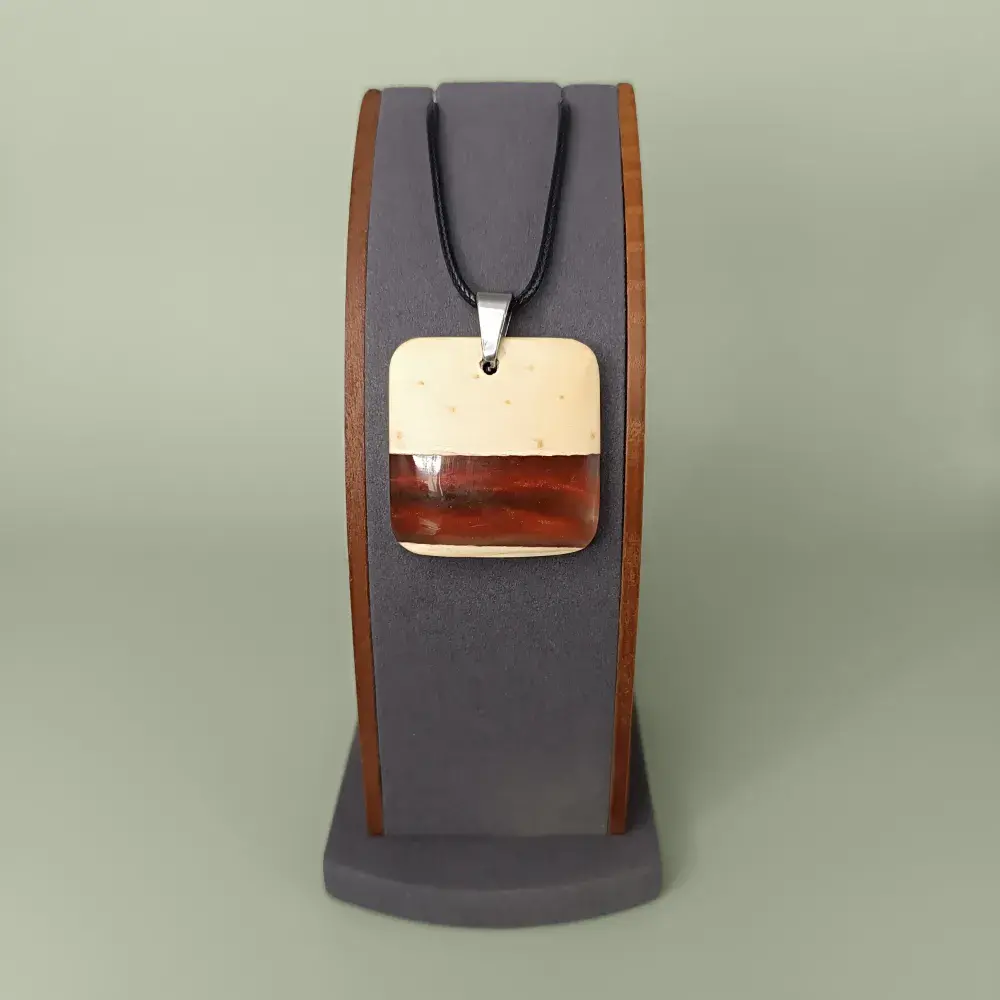 Pendentif carré en bois de pin et résine rouge-orange, vue de face sur présentoir.