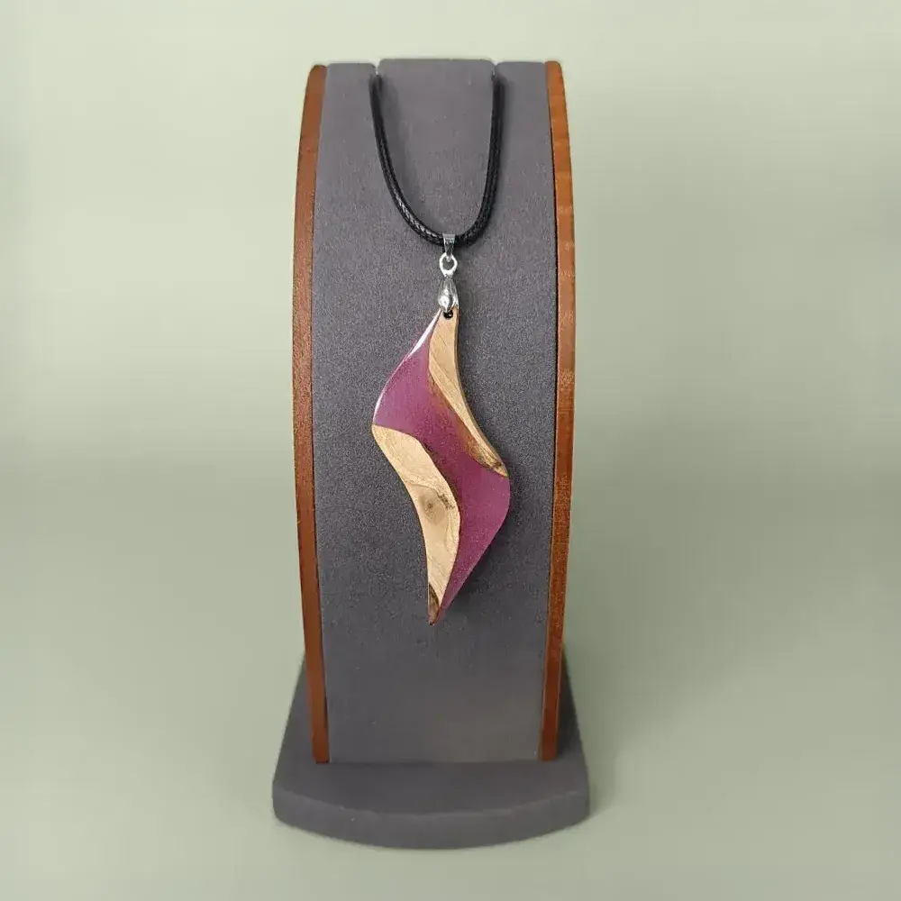 Pendentif artisanal en bois et résine pourpre, vue de face sur présentoir.