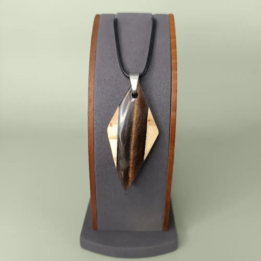 Pendentif artisanal en bois clair et résine brun irisé, vue de face sur présentoir.