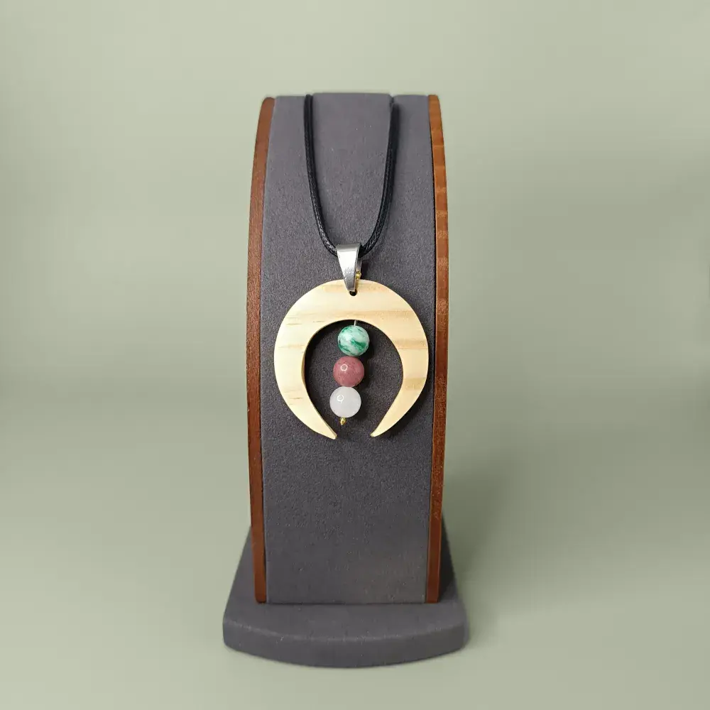 Pendentif en bois naturel avec trois pierres fines, sur présentoir, style élégant.