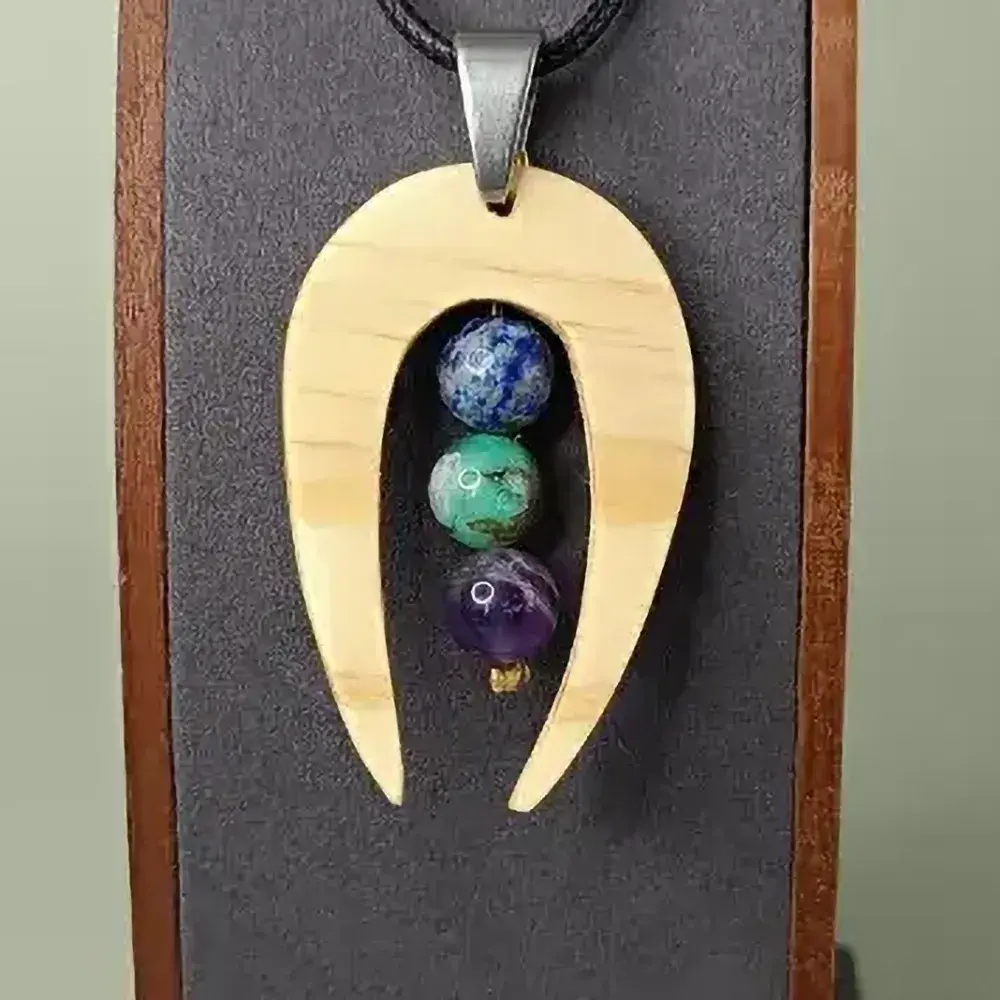 Pendentif en bois naturel avec trois pierres fines, forme allongée, artisanal et élégant.
