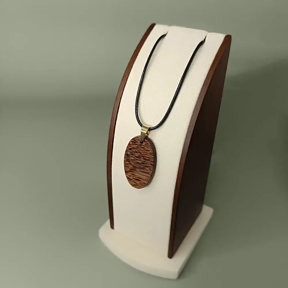 Vue latérale et plongeant du pendentif Sombre Essence en bois de Wacapou, forme ovale, veinages brun foncé subtils.