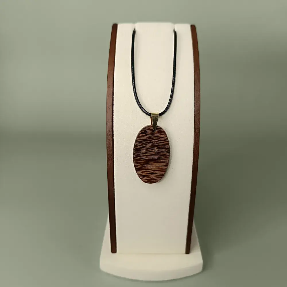 Vue de face du pendentif Sombre Essence en bois de Wacapou, forme ovale, veinages brun foncé subtils.