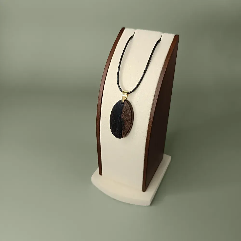 Vue latérale et plongeante du pendentif Sombre Éclat en bois de Ziricote, forme ovale, veinages noirs et bruns.