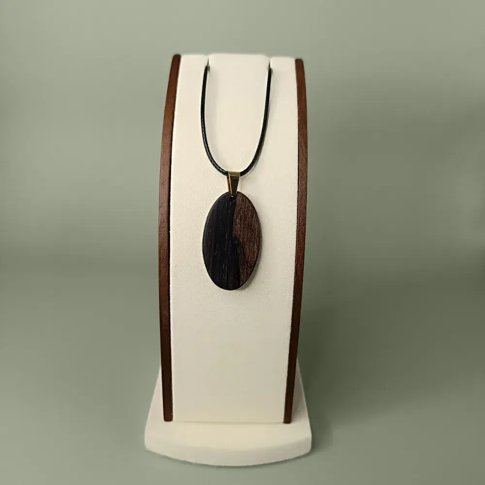 Vue de face du pendentif Sombre Éclat en bois de Ziricote, forme ovale, veinages noirs et bruns.
