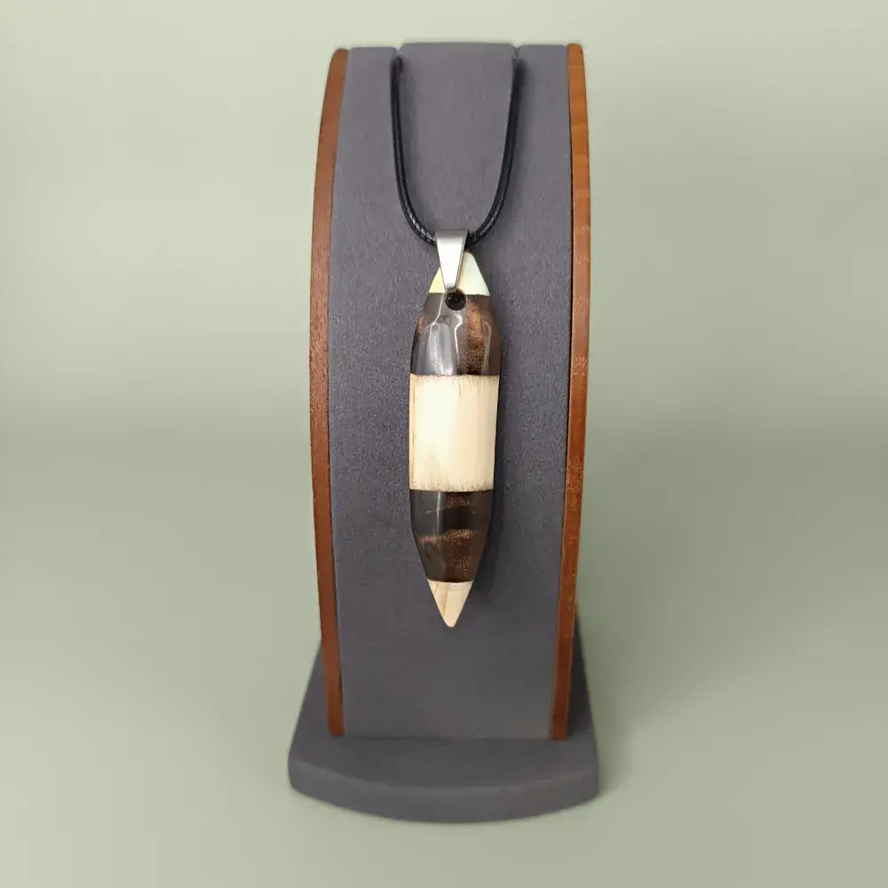 Pendentif en bois de pin et résine marron, posé de face sur un présentoir.