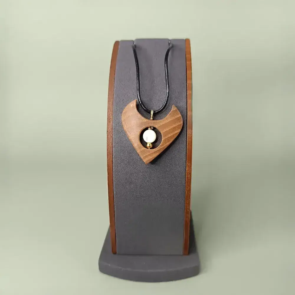 Pendentif en bois naturel avec nacre blanche, présenté de face sur un présentoir, semi-luxueux et poétique.