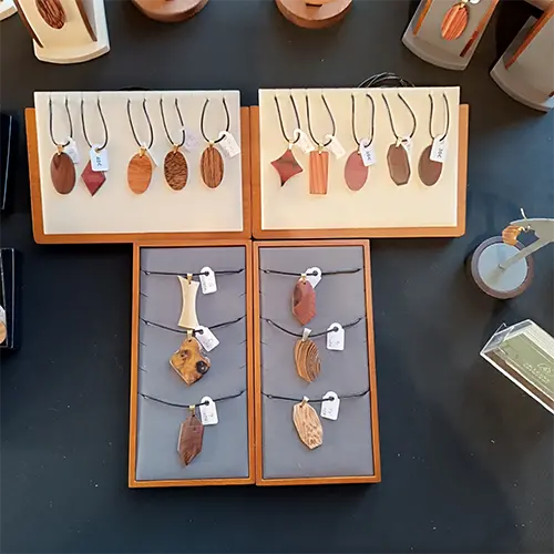 Pendentifs et bijoux artisanaux en bois présentés sur le stand Skyline Artwood.