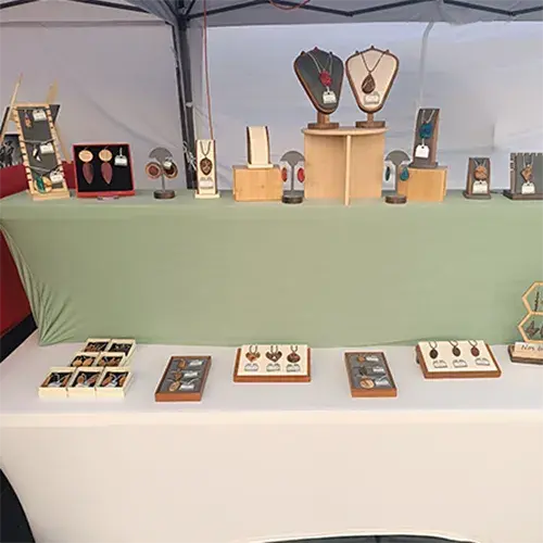 Stand Skyline Artwood sur un marché artisanal, présentant des bijoux en bois faits main.