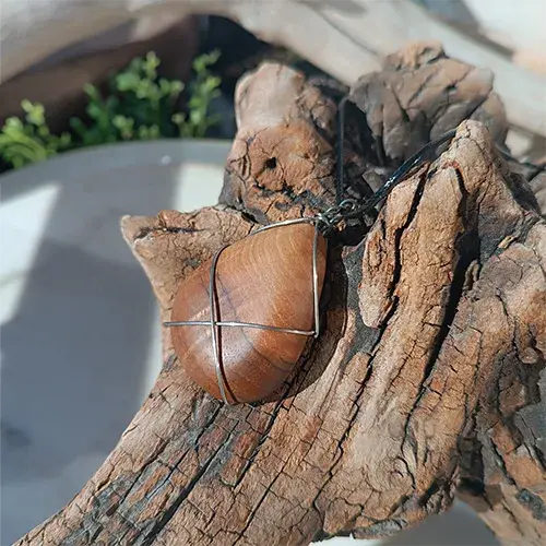 Pendentif Sillage d’Acier en bois et fil d’acier inoxydable 316L présenté sur bois flotté.